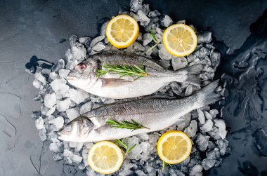 Soğuk ezilmiş buz yığını üzerinde limon dilimleri ve biberiye ile taze balık yakın görünümü