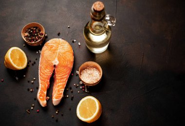 Siyah taş arka plan üzerinde baharat ve limon ile taze çiğ somon biftek