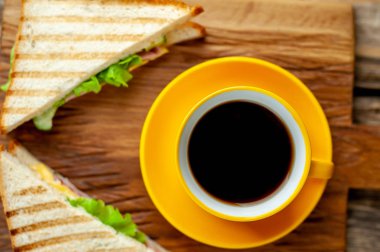 Jambon ve peynir ile taze ızgara sandviç ahşap doğrama tahtası üzerinde kahve fincan ile servis