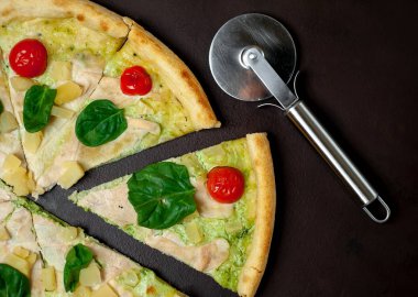 siyah taş arka plan üzerinde kiraz domates ve taze ıspanak yaprakları ile pizza