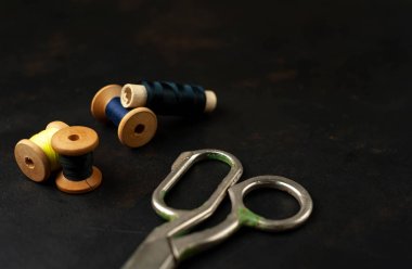 siyah arka plan üzerinde dikiş makaraları yığını ile terzi makasları 