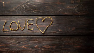 Kahverengi ahşap arka plan üzerinde ipliklerden yapılmış yazı aşk 