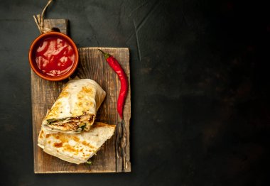 Ahşap doğrama tahtası üzerinde baharatlı sos ile tavuk ve sebze ile sarılmış geleneksel Meksika burrito 