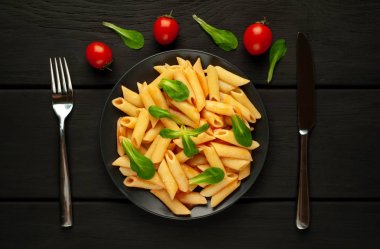 domates soslu makarna, yeşil yapraklar ve taş siyah arka plan üzerinde olgun domates