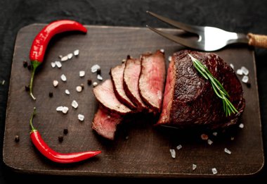 Siyah taş arka plan üzerinde baharat ve biberiye dal ile Taze ızgara biftek