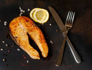 Siyah taş arka plan üzerinde baharat ve limon ile ızgara somon biftek