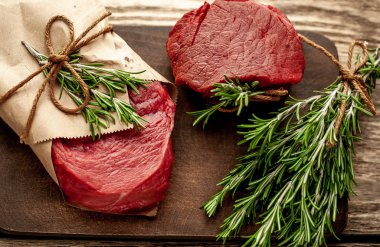 Ahşap arka plan üzerinde zanaat kağıt sarılmış baharat ile Çiğ biftek 