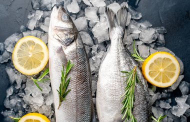 Soğuk ezilmiş buz yığını üzerinde limon dilimleri ve biberiye ile taze balık yakın görünümü