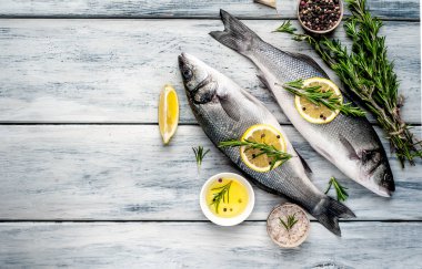 Gri ahşap arka plan üzerinde limon dilimleri ve biberiye dalları ile çiğ balık
