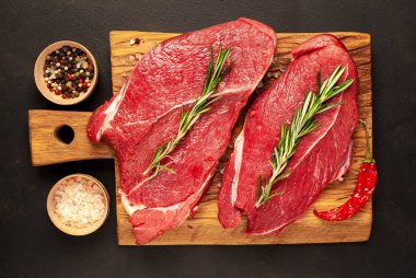 Taş arka planda baharat ve biberiye ile çiğ sığır biftek