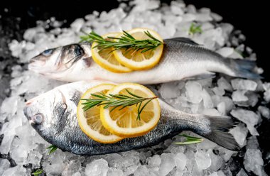 Soğuk ezilmiş buz yığını üzerinde limon dilimleri ve biberiye ile taze balık yakın görünümü