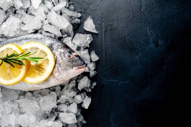 Soğuk ezilmiş buz yığını üzerinde limon dilimleri ve biberiye ile taze balık yakın görünümü
