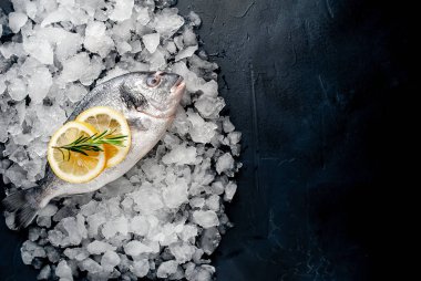 Soğuk ezilmiş buz yığını üzerinde limon dilimleri ve biberiye ile taze balık yakın görünümü
