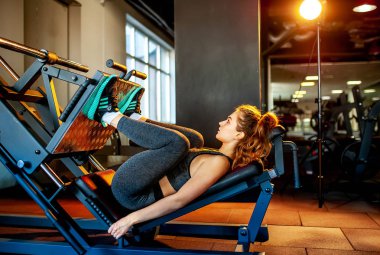 Genç sporcu kadın boş spor salonunda kas çalıştırıyor.  