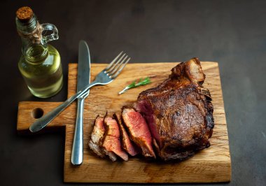 Siyah taş arka plan üzerinde ahşap doğrama tahtası üzerinde baharat ile Yağlı ızgara domuz biftek