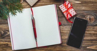 Eski ahşap arka plan üzerinde kırmızı yay ve boş defter ile hediye kutuları yığını 