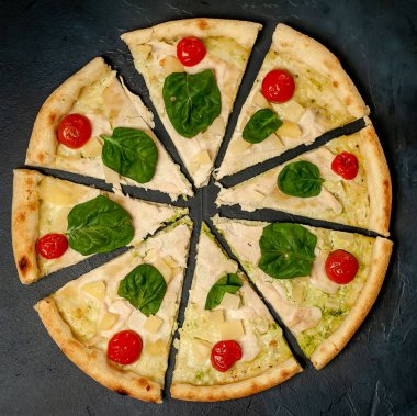 siyah taş arka plan üzerinde kiraz domates ve taze ıspanak yaprakları ile pizza