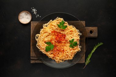 koyu taş arka plan üzerinde domates sosu ve maydanoz yaprakları ile İtalyan spagetti makarna