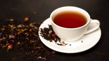 siyah arka plan üzerinde çiçek demlemek yığını ile taze çay fincan