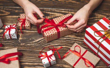 Eski ahşap arka plan üzerinde kırmızı yay ile kadın elleri dekorasyon hediye kutuları 