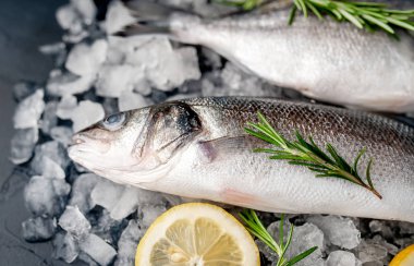 Soğuk ezilmiş buz yığını üzerinde limon dilimi ve biberiye ile taze balık yakın görünümü
