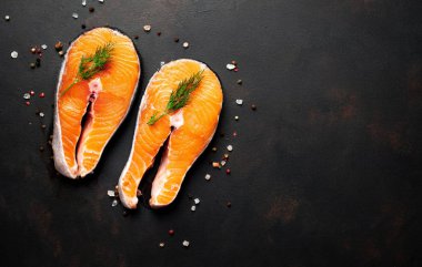 Siyah taş arka plan üzerinde baharat ve dereotu ile taze çiğ somon biftek