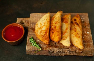Ahşap doğrama tahtası üzerinde domates soslu Geleneksel Latin Amerika kızarmış empanadas 