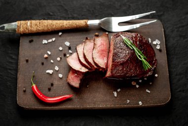 Siyah taş arka plan üzerinde baharat ve biberiye dal ile Taze ızgara biftek