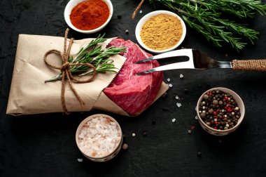 Siyah taş arka plan üzerinde baharat ile Çiğ taze biftek