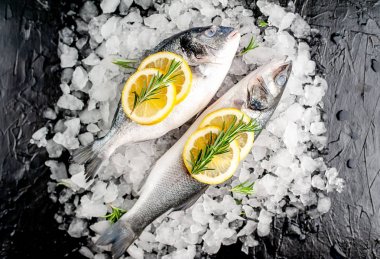 Soğuk ezilmiş buz yığını üzerinde limon dilimleri ve biberiye ile taze balık yakın görünümü