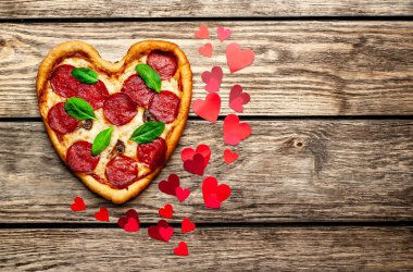 salam ve taze fesleğen yaprakları ile peynir kalp pizza kalp şekli kırmızı konfeti ile ahşap arka plan üzerinde 