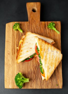 Ahşap doğrama tahtasında jambon, taze brokoli ve peynirile taze ızgara sandviçler