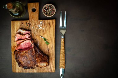 Siyah taş arka plan üzerinde ahşap doğrama tahtası üzerinde baharat ile Yağlı ızgara domuz biftek