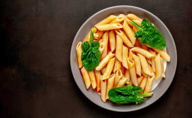 taş siyah arka plan üzerinde yeşil yaprakları ile servis domates soslu makarna