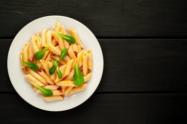 taş siyah arka plan üzerinde yeşil yaprakları ile servis domates soslu makarna