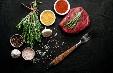 Siyah taş arka plan üzerinde baharat ile Çiğ taze biftek
