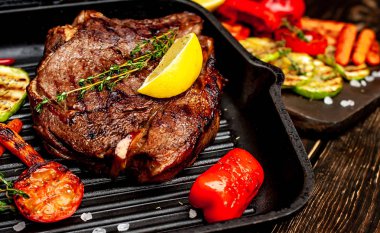 Taze ızgara biftek ahşap arka plan üzerinde sebze ile servis