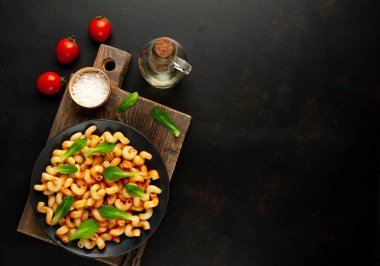 taş siyah arka plan üzerinde ahşap doğrama tahtası üzerinde domates soslu makarna