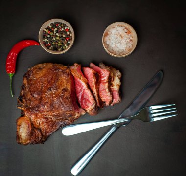 Siyah taş arka plan üzerinde baharat ve biber ile Yağlı ızgara domuz biftek