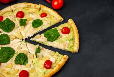 siyah taş arka plan üzerinde kiraz domates ve taze ıspanak yaprakları ile pizza