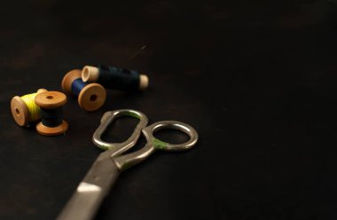 siyah arka plan üzerinde dikiş makaraları yığını ile terzi makasları 