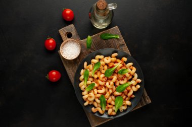 taş siyah arka plan üzerinde ahşap doğrama tahtası üzerinde domates soslu makarna