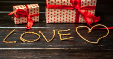 Hediye kutuları ve ahşap arka plan üzerinde ipliklerden yapılmış yazı aşk