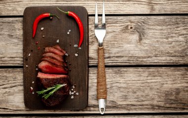 Ahşap arka planda baharat ve biberiye dalları ile taze ızgara biftek
