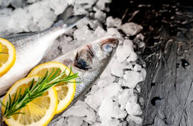 Soğuk ezilmiş buz yığını üzerinde limon dilimleri ve biberiye ile taze balık yakın görünümü