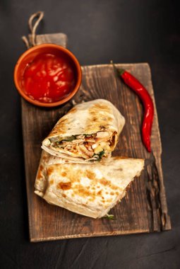 Ahşap doğrama tahtası üzerinde baharatlı sos ile tavuk ve sebze ile sarılmış geleneksel Meksika burrito 