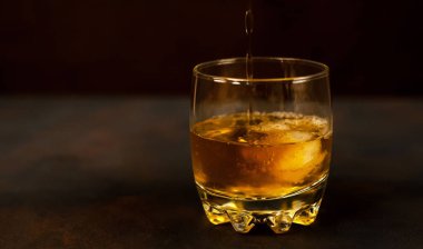 Siyah arka planda bir bardak buz viskisi