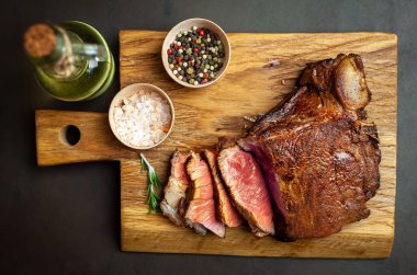 Siyah taş arka plan üzerinde ahşap doğrama tahtası üzerinde baharat ile Yağlı ızgara domuz biftek