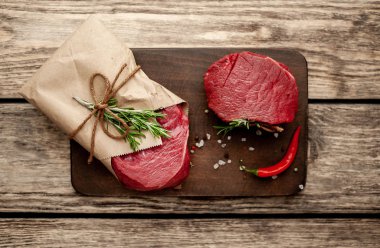 Ahşap arka plan üzerinde zanaat kağıt sarılmış baharat ile Çiğ biftek 