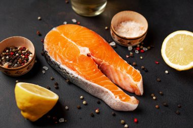 Siyah taş arka plan üzerinde baharat ve limon ile taze çiğ somon biftek